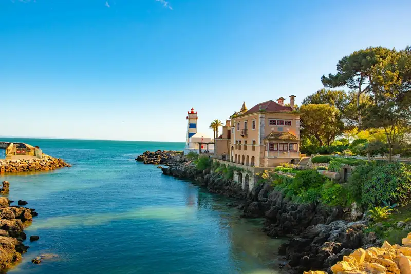 Enseada de Santa Marta em Cascais, com o farol e a casa senhorial sobre as rochas